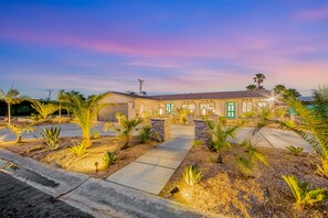 A hotel with a paved driveway, stone pillars, and palm trees. - Designer dream with fireplace, game room, private pool, outdoor kitchen, firepit (Palm Springs)