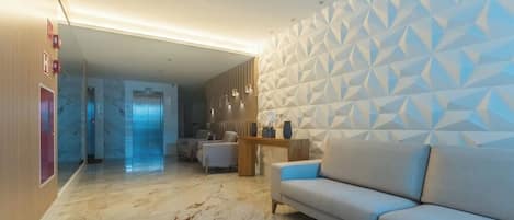 Un moderno vestíbulo de hotel con piso de mármol, un sofá y una pared con diseño geométrico.