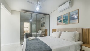 A bedroom with a bed, a bedside table, a nightstand, a ceiling fan, an air conditioning unit, a sliding glass door, and a wall with three framed pictures. - Apt in Condo With Easy Access to the sea Are1502 (Guarapari)