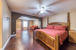 A spacious bedroom with a large bed, a ceiling fan, and a view to an adjacent room. - Beautiful & spacious home with private pool, spa, and basketball hoop (Indio)