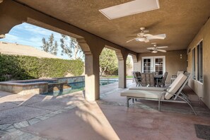 A covered patio area with a pool, outdoor seating, and a ceiling fan. - Beautiful & spacious home with private pool, spa, and basketball hoop (Indio)