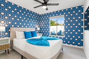 A bedroom with a bed, a nightstand, a ceiling fan, and a window with a view of the outside. - Amazing dog-friendly home with enclosed yard, firepit, pool, & washer/dryer (Palm Springs)