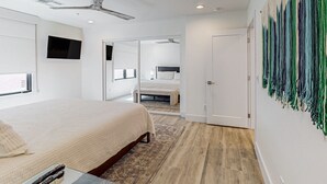 A modern bedroom with a bed, a flat-screen TV, a ceiling fan, and a large abstract painting on the wall. - Indulge in Luxury and Comfort in Scottsdale, AZ where cozy meets chic (Scottsdale)