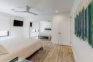 A modern bedroom with a bed, a flat-screen TV, a ceiling fan, and a large abstract painting on the wall. - Indulge in Luxury and Comfort in Scottsdale, AZ where cozy meets chic (Scottsdale)