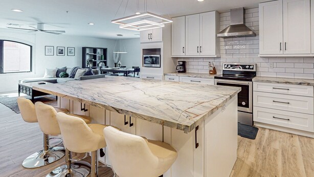 A modern kitchen with a marble island, white cabinets, and stainless steel appliances. - Indulge in Luxury and Comfort in Scottsdale, AZ where cozy meets chic (Scottsdale)