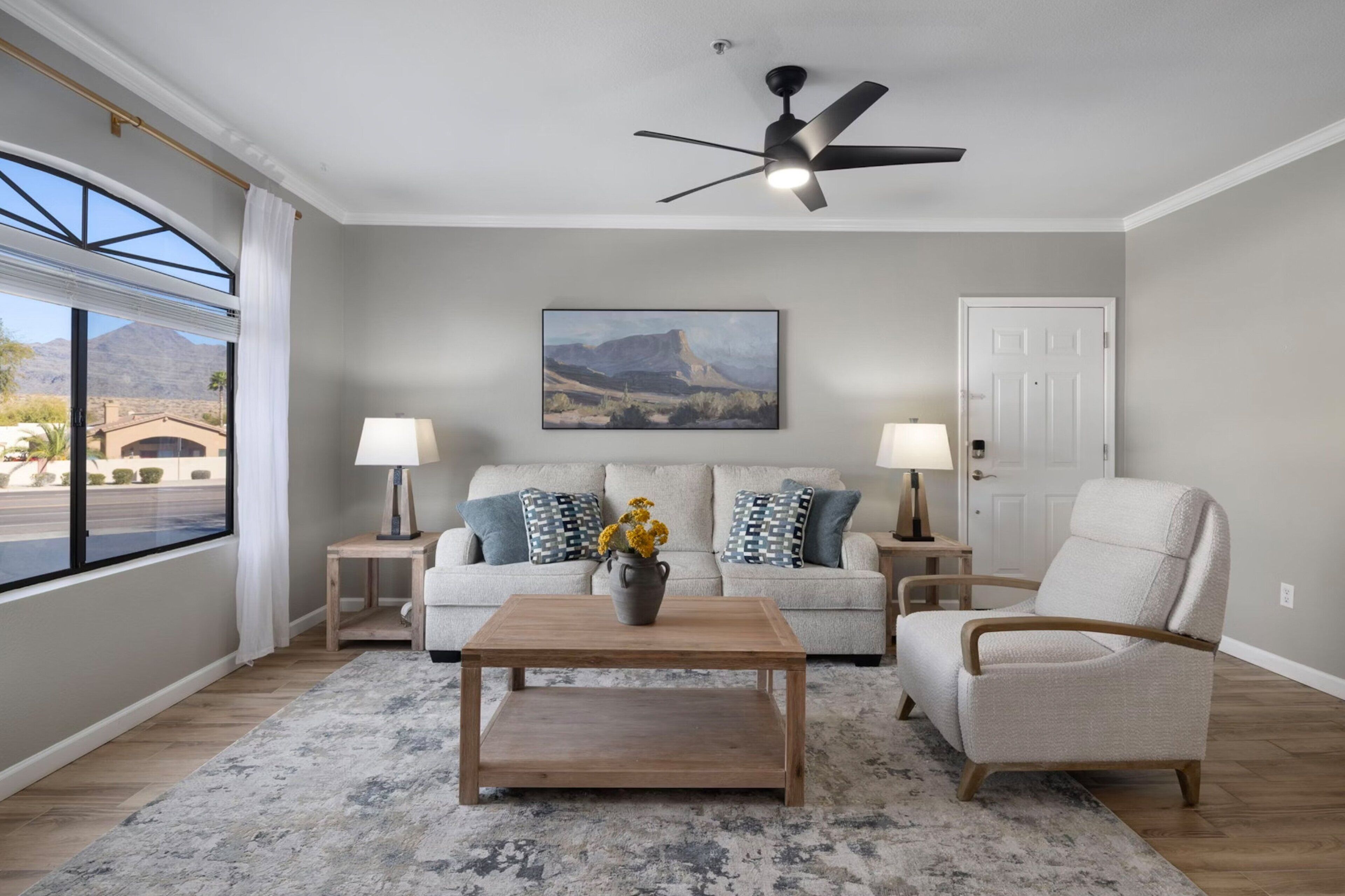 A living room with a sofa, armchairs, a coffee table, and a ceiling fan.