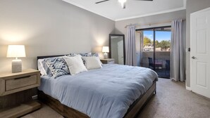 A bedroom with a bed, nightstands, a ceiling fan, a sliding glass door, and a view of the outdoors. - Scottsdale Bliss – Stylish Long Term, Comfort, and Mountain Views Await! (Scottsdale)