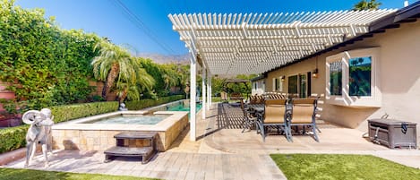 Un patio con piscina, mobiliario exterior y una pérgola.