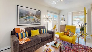 Un salon moderne avec un canapé marron, un fauteuil jaune et un tapis coloré.