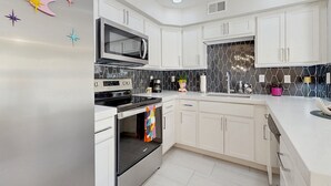 Une cuisine moderne avec des meubles blancs, un réfrigérateur en acier inoxydable, un four à micro-ondes et une cuisinière.