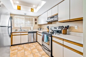 A compact kitchen with white cabinets, a stainless steel refrigerator, a dishwasher, and a stove. - Beautiful condo near downtown w/ shared pools - golf on-site (Palm Springs)