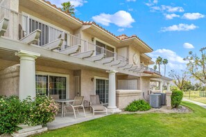 A two-story house with a covered patio, outdoor seating, and a garage. - Beautiful condo near downtown w/ shared pools - golf on-site (Palm Springs)