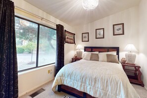 A bedroom with a large bed, two bedside tables with lamps, a window with curtains, and framed pictures on the wall. - Cozy home with BBQ grill, fireplace, patio, hiking nearby (Sedona)