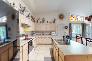 A modern kitchen with light wood cabinets, a central island, stainless steel appliances, and various decorative items on the walls. - Cozy home with BBQ grill, fireplace, patio, hiking nearby (Sedona)