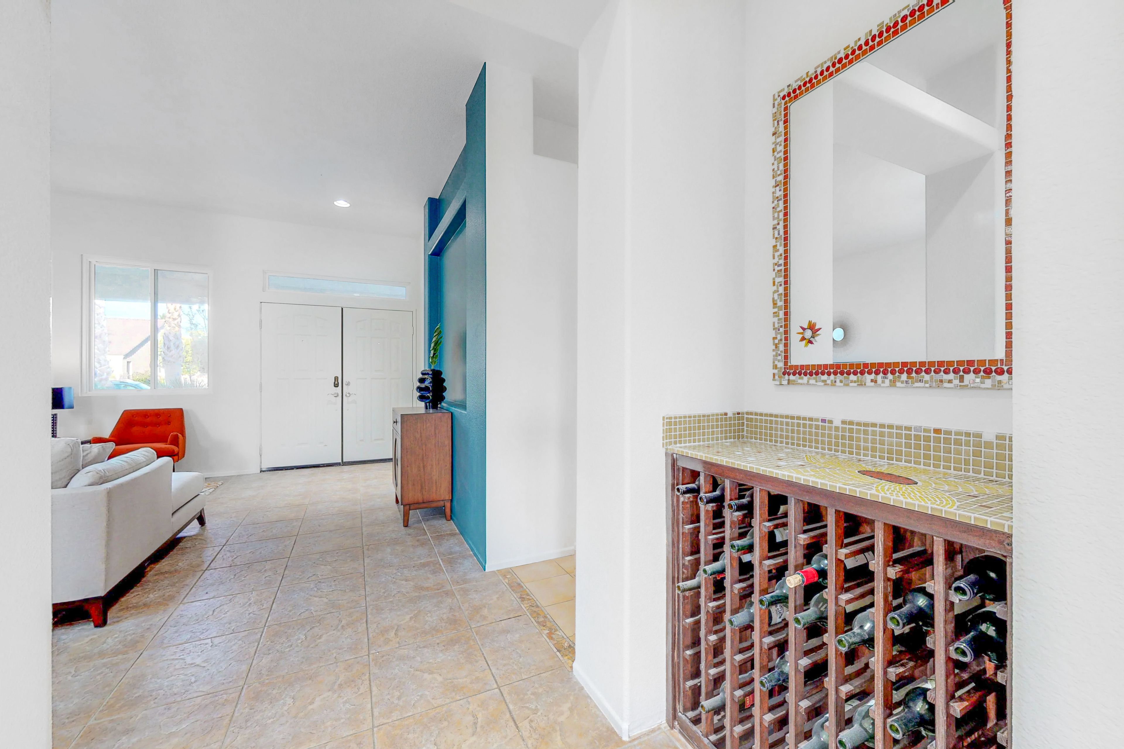 A modern interior with a white sofa, a wooden cabinet, a wine rack, and a tiled backsplash.