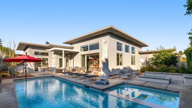 Ein modernes, zweistöckiges Haus mit Swimmingpool, Sitzgelegenheit im Freien und einer Terrassenfläche.