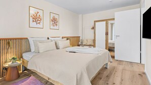 A modern bedroom with a large bed, a bedside table, a lamp, and a wall-mounted TV. - The View B04 Briese - Garden furniture, elevator, shared Sauna, parking space (Dagebüll)