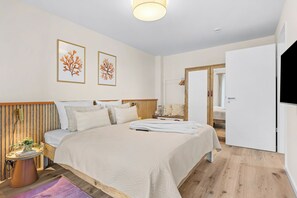 A modern bedroom with a large bed, a bedside table, a lamp, and a wall-mounted TV. - The View B04 Briese - Garden furniture, elevator, shared Sauna, parking space (Dagebüll)