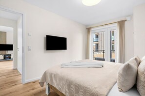 Een slaapkamer met een bed, een televisie en uitzicht op een balkon.