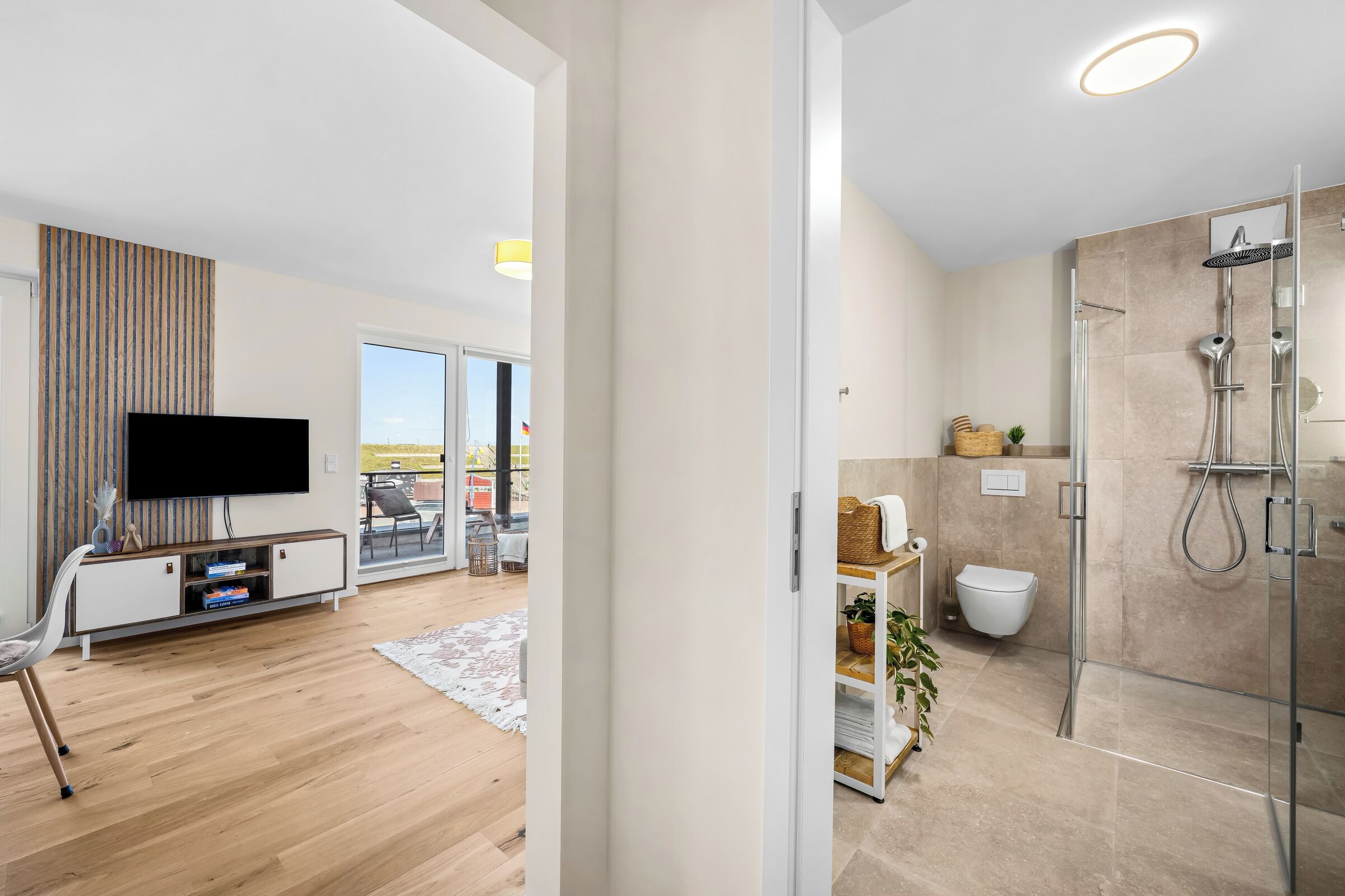 Et moderne badeværelse med en glasafskærmet brusekabine, toilet og håndvask.