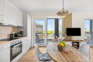 A modern kitchen with a dining area, a flat-screen TV, and a view of the outdoors. - The View B04 Briese - Garden furniture, elevator, shared Sauna, parking space (Dagebüll)