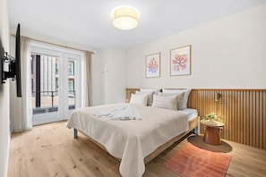 A hotel room with a bed, a wooden headboard, a small table with a plant, and a view through the glass doors. - The View B04 Briese - Garden furniture, elevator, shared Sauna, parking space (Dagebüll)