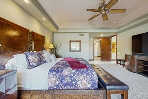 A spacious bedroom with a large bed, a wooden headboard, a ceiling fan, and a television. - Glamorous home w/ mountain views, private pool, & on-site golf - 3 BR - #067092 (La Quinta)