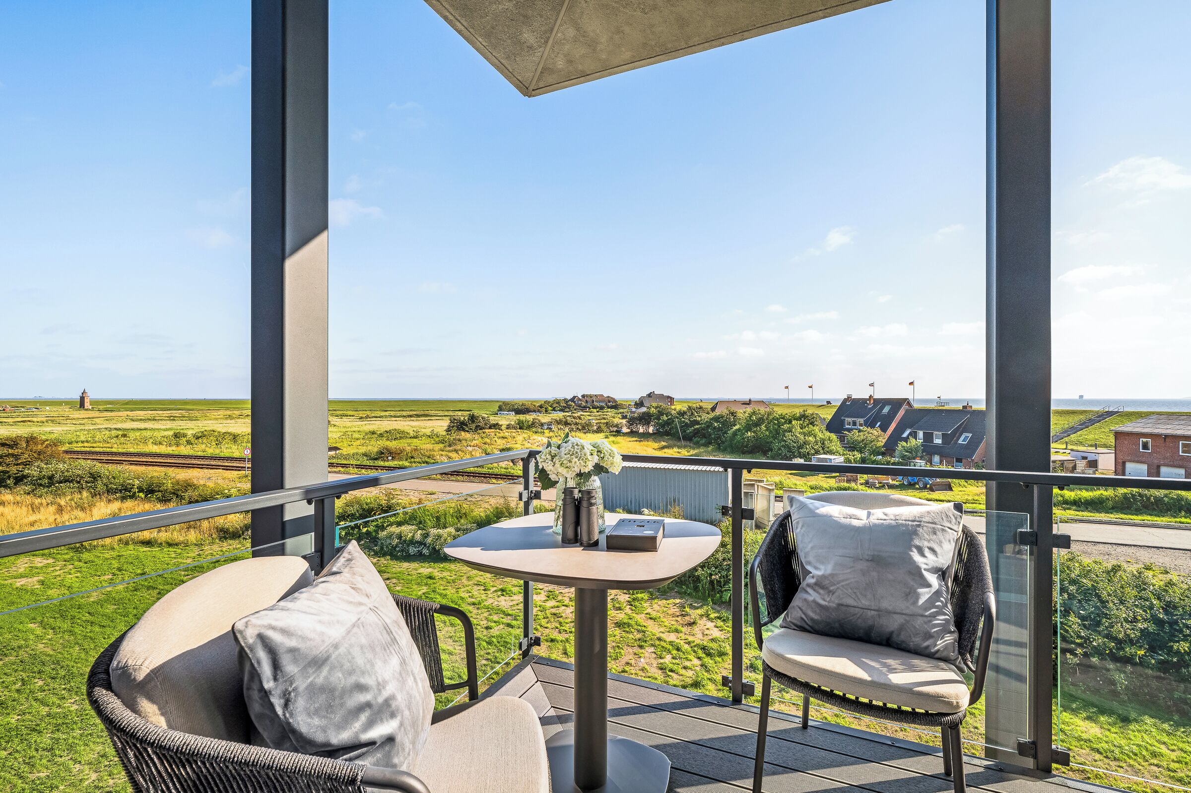 A balcony with a table, chairs, and a view of the countryside.