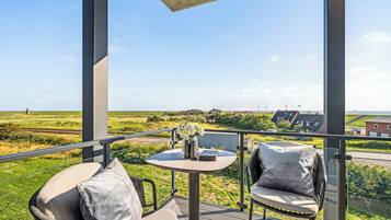 A balcony with a table, chairs, and a view of the countryside.
