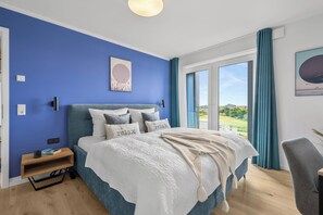 A bedroom with a large bed, a nightstand, a chair, and a view of the outdoors. - The View B12 Zuhause bei Emi -Sea view,elevator, balcony, armchair, shared Sauna (Dagebüll)