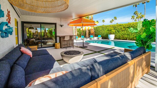 A modern outdoor seating area with a pool, wicker furniture, and a large umbrella. - Mtn-view home with private pool, large patio, streaming, fireplace, grill, & W/D (Palm Springs)