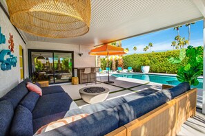 A modern outdoor seating area with a pool, wicker furniture, and a large umbrella. - Mtn-view home with private pool, large patio, streaming, fireplace, grill, & W/D (Palm Springs)