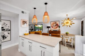A modern kitchen with white cabinets, a marble countertop, and pendant lighting. - Mtn-view home with private pool, large patio, streaming, fireplace, grill, & W/D (Palm Springs)