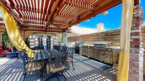 An outdoor patio with a covered dining area, a grill, and a brick wall. - Family-Friendly Home w/ an Outdoor Kitchen, Private Pool, & Spa - 3BR - #66708 (La Quinta)