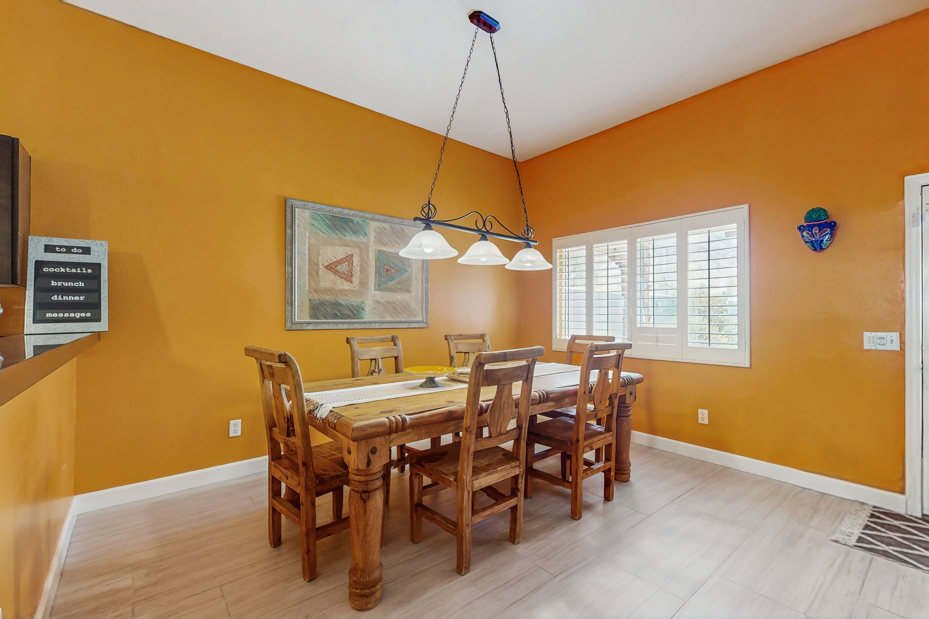 Un coin repas avec une table en bois, des chaises et un luminaire suspendu.
