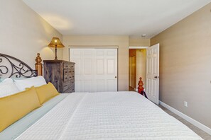 Une chambre à coucher avec un lit, une commode, une lampe et une porte.
