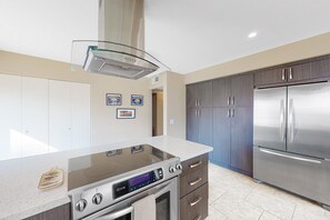 A modern kitchen with a stainless steel refrigerator, a built-in oven, and a glass cooktop. - home w/ a patio & shared pool plus fairway & mountain views (Rancho Mirage)