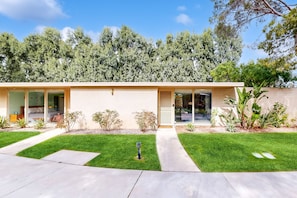 A modern two-story house with a flat roof, large glass windows, and a well-maintained lawn. - Well-designed & modern villa with patios, pool & hot tub - walk to downtown (Palm Springs)