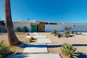Una casa moderna con fachada de piedra, una puerta verde y un camino que lleva a la entrada.