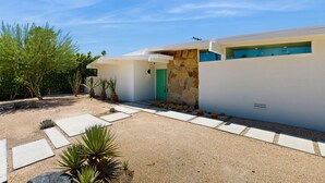 Une maison moderne avec une façade en pierre, une porte verte et un ciel dégagé.