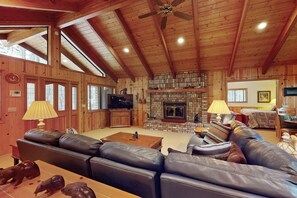 A spacious living room with a fireplace, leather sofas, and a television. - Cabin on the golf course with fire pit, BBQ grill, and games (Pinetop)