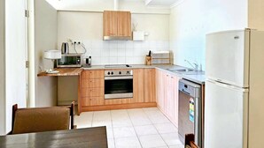 Una cocina compacta con armarios de madera, horno empotrado, microondas y refrigerador.