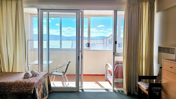 Habitación de hotel con cama, una silla, un escritorio y vistas al exterior.
