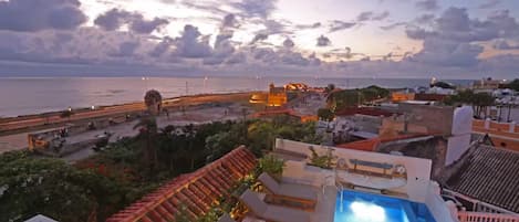 Una piscina en la azotea con vistas al mar y una fortaleza histórica.