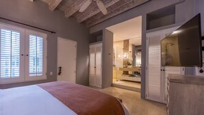 Un dormitorio con cama, armario y baño visible a través de una puerta abierta.