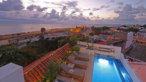 Una piscina en la azotea con vistas al mar y una fortaleza histórica.