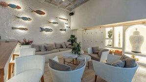 A modern living room with a white sofa, wicker chairs, and a dining area. - HOTEL NOI 1860: LUXURY HOUSE CARTAGENA DE INDIAS - King bed (Cartagena de Indias)