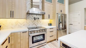 A modern kitchen with wooden cabinets, a stainless steel range, and a built-in oven. - A stately luxury house with pool nestled in a serene neighborhood (Scottsdale)