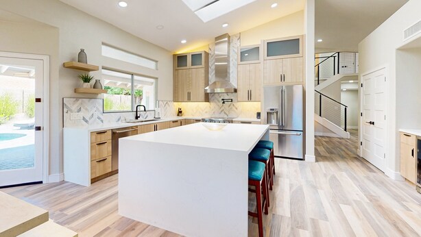A modern kitchen with a large island, wooden cabinets, and a built-in stove. - A stately luxury house with pool nestled in a serene neighborhood (Scottsdale)