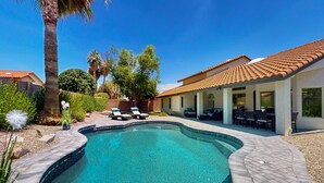 A swimming pool with a curved edge, surrounded by a patio area with lounge chairs and a covered seating area. - A stately luxury house with pool nestled in a serene neighborhood (Scottsdale)